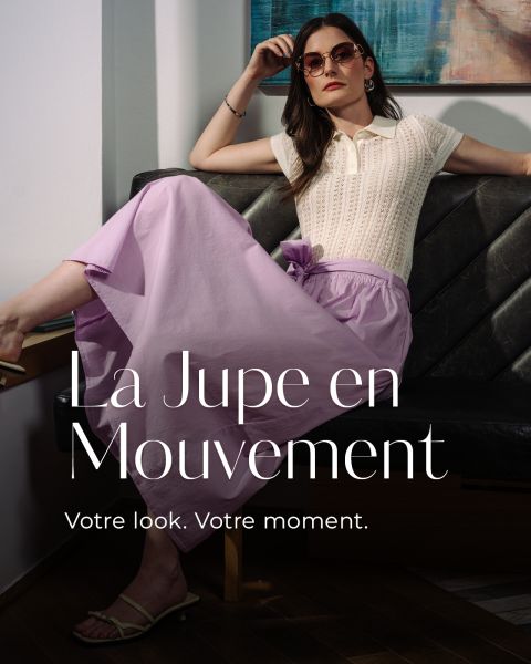 Une femme avec des lunettes de soleil et un léger tricot pose sur un banc et porte une jupe lavande fluide. Le texte est : "La Jupe en Mouvement. Votre look. Votre moment."