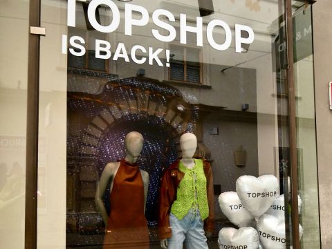 Vitrine avec un panneau "TOPSHOP IS BACK !", deux mannequins portant des tenues tendance et des ballons blancs en forme de cœur avec l'inscription "TOPSHOP".