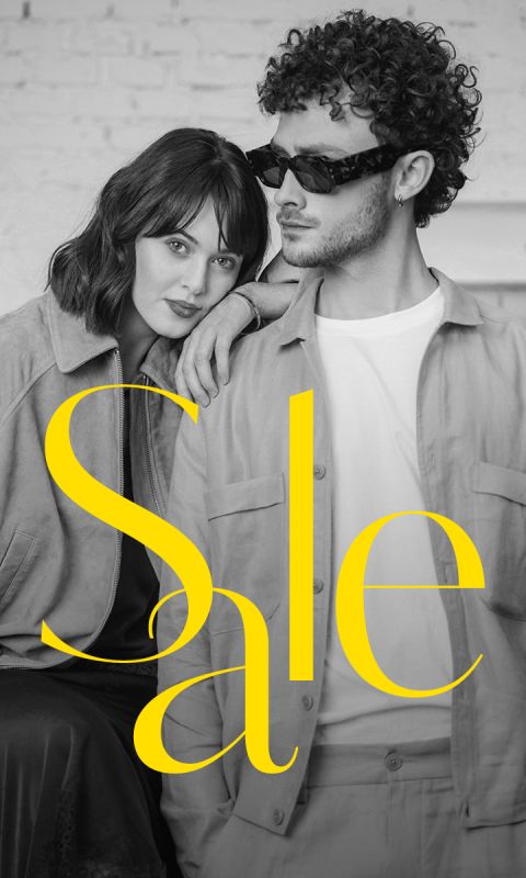 Une femme élégante et un homme en tenues tendance posent ensemble avec "Soldes" en grands caractères jaunes au-dessus de l'image.