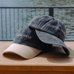 Deux casquettes de baseball sur une surface en bois au bord de l'eau ; sur l'une est écrit "ASK ME FOR ID" et sur l'autre "Formentera Social Club".