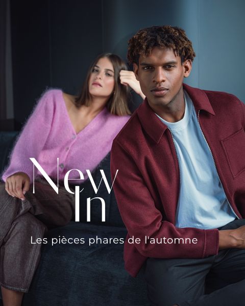 Une femme dans un pull rose et un homme dans une veste bordeaux posent sur un canapé. Le texte indique « Nouveautés » et « Les pièces phares de l'automne ».