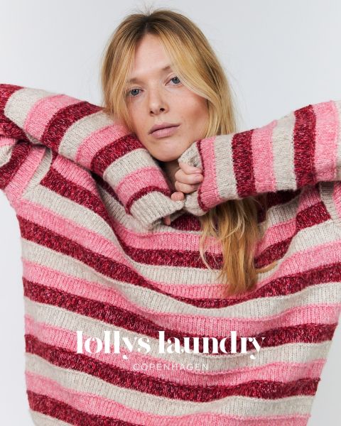 Une femme en pull rayé rose et rouge, posant les bras levés devant un fond blanc. En bas, l'inscription « Lollys Laundry Copenhagen ».