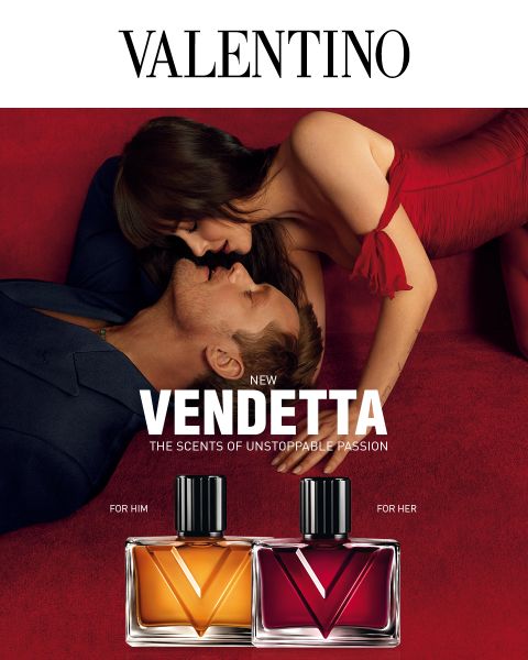 Un homme et une femme en tenue élégante s'étreignent sur du velours rouge à côté des flacons de parfum « Valentino Vendetta », l'un étiqueté « For Him » et l'autre « For Her ».