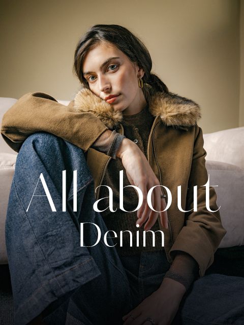 Une femme portant une veste marron à col de fourrure et un jean sur lequel est écrit « All about Denim ».