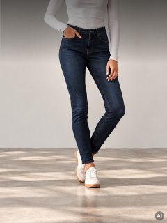 Une personne portant une chemise blanche à manches longues, un jean skinny bleu foncé et des baskets blanches.