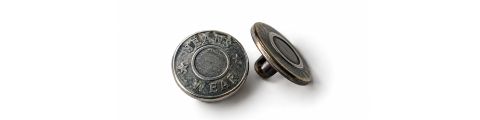 Deux boutons de jean en métal, l'un debout et affichant l'inscription « JEANS WEAR », l'autre à plat ; les deux ont un centre rond et une surface d'aspect antique.